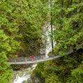 Woman in red rain jacket standing on a suspension bridge and looking at the Cascade falls, in Cascade falls regional park, Deroche Royalty Free Stock Photo