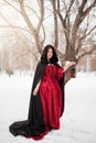 woman in a red rococo dress and a raincoat with a fur hood is walking with a lantern in her hands Royalty Free Stock Photo