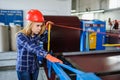 Woman in red safety helmet at metal tile roof manufacturing fact