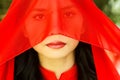 Woman with red scarf covering her face