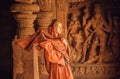 Woman in red scarf walking inside the 6th century Hindu temple with ancient caves and artworks, Karnataka of India