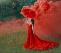 Woman in red silk long dress train with umbrella. Art design photography.