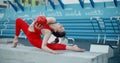 Woman in red sports costume performing callisthenics exercises with gymnastic ball at workout playground outdoors