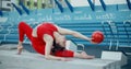 Woman in red sports costume performs callisthenics exercises with gymnastic ball on the bench at workout playground