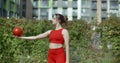 Woman in red sports costume performs callisthenics exercises with gymnastic ball outdoors, sports in the urban