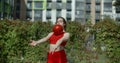 Woman in red sports costume performs callisthenics exercises with gymnastic ball outdoors, sports in the urban