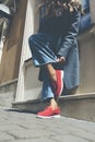 Woman in a red stylish suede loafer shoes, blue jeanse, white shirt and trendy checkered coat posing on the street. Pair Royalty Free Stock Photo