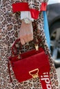 Woman with red suede Coccinelle bag and Rolex watch before Giorgio Armani fashion show, Milan Fashion Week