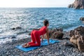Selective focus. Young beautiful caucasian woman in a red suit practicing yoga, fitness and stretching on the beach at