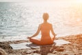 Woman sea yoga. Selective focus. Young beautiful caucasian woman in a red suit practicing yoga on the beach at sunrise Royalty Free Stock Photo