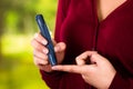 Woman with red sweater checking blood sugar level by glucometer and test stripe at home Royalty Free Stock Photo