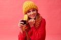 Girl in a red sweater and knitted hat holding a cup of hot mulled wine with an orange slice. Red background. Studio Royalty Free Stock Photo