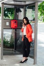 Beautiful woman in red talking on street phone in a phone booth Royalty Free Stock Photo