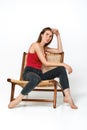 Woman in tank-top and jeans sits on a wicker chair