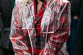 Woman with red tartan jacket and transparent raincoat before Fendi fashion show, Milan Fashion Week street