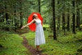 Woman with red umbrella celebrates in a forest under rain