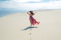 Woman in red waving dress with flying fabric runs on background of dunes Royalty Free Stock Photo