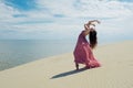 Woman in red waving dress with flying fabric runs on background of dunes. Gymnast on the back of the dune Royalty Free Stock Photo