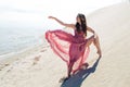 Woman in red waving dress with flying fabric runs on background of dunes. Gymnast on the back of the dune Royalty Free Stock Photo