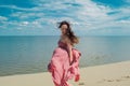 Woman in red waving dress with flying fabric runs on background of dunes. Royalty Free Stock Photo