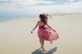 Woman in red waving dress with flying fabric runs far away, back view. Royalty Free Stock Photo