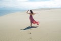 Woman in red waving dress with flying fabric runs far away, back view. Royalty Free Stock Photo