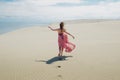 Woman in red waving dress with flying fabric runs far away, back view. Royalty Free Stock Photo