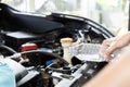 A woman refilling the radiator of her car. She is standing next to the open hood of the car, holding a bottle of water Royalty Free Stock Photo