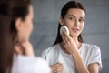 Woman reflecting in mirror holding facial sponge cleanses face