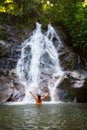 Woman refreshing herself in beautiful waterfall