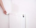 A woman regulates the temperature of the radiator heating with a thermostat. Wall mounted heat radiator in the bathroom, copy Royalty Free Stock Photo