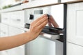 Woman regulating cooking mode on oven panel in kitchen,