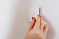 Woman regulating temperature on home heating thermostat