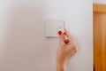 Woman regulating temperature on home heating thermostat