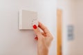 Woman regulating temperature on home heating thermostat