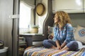 Woman and relax indoor leisure activity alone. One female people sitting on bedroom inside camper van and looking outside the