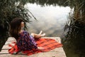 Young woman position on a wooden pier by the lake