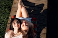 Two teenager girls sitting on a pier at the river bank having good time in summer. happy girl friends relaxing outdoor near lake.