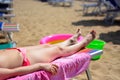 The woman relaxes lying on the deckchair in the sun with the games of her children on the sand Royalty Free Stock Photo