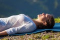 Woman relaxes in yoga asana Savasana outdoors