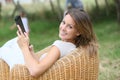 Woman relaxing in armchair in garden using tablet