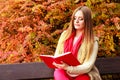 Woman relaxing in autumnal park reading book