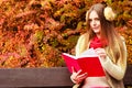 Woman relaxing in autumnal park reading book