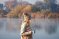 Woman relaxing with coffee next to lake at autumn cold morning