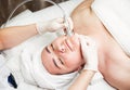 Woman relaxing while cosmetologist using massage device on her face