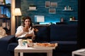 Woman relaxing on couch holding beer bottle while eating tasty delicious burger Royalty Free Stock Photo