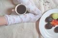 Woman relaxing in cozy place with sweets and a cup of tea. Royalty Free Stock Photo