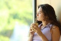 Woman relaxing drinking coffee looking through a window Royalty Free Stock Photo