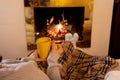 Woman relaxing by the fireplace warming up feet in woolen with a cup of hot drink socks and blanket Royalty Free Stock Photo