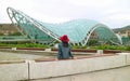 Woman Relaxing in front of the Bridge of Peace, a Famous Landmark of Tbilisi, Capital of Georgia